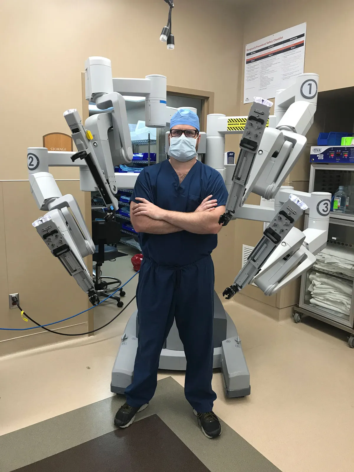 Dr. Daniel Gay standing in front of the da Vinci Robotic Surgery machine