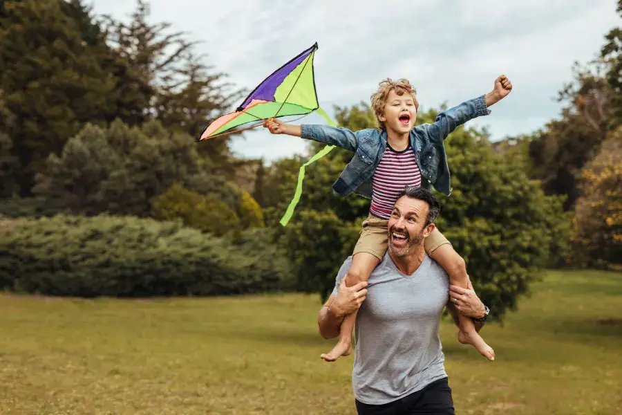 Person with child flying a kite on their shoulder | Capital Surgical Shoulders Boise