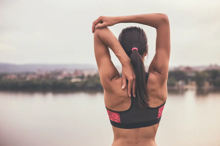Woman stretching by lake | Captial Surgical Stenosis Surgery Boise